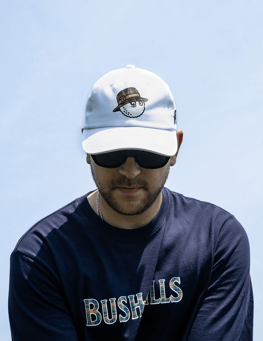 Man wearing Bushmills x Malbon white hat on golf course.