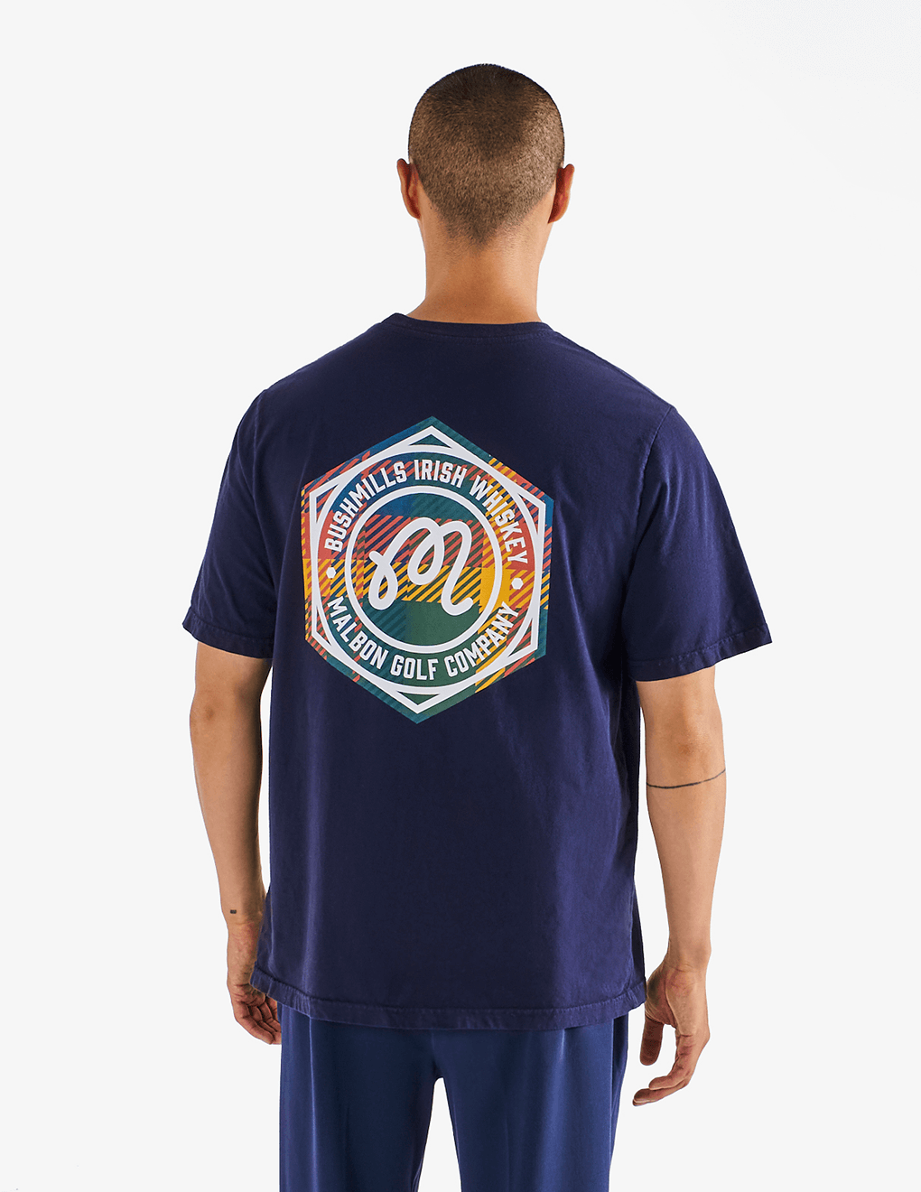 Model wearing of Bushmills x Malbon navy t-shirt, showing back of shirt with collab logo.