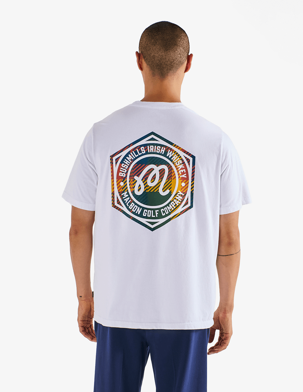 Model wearing of Bushmills x Malbon white t-shirt, showing back of shirt with collab logo.