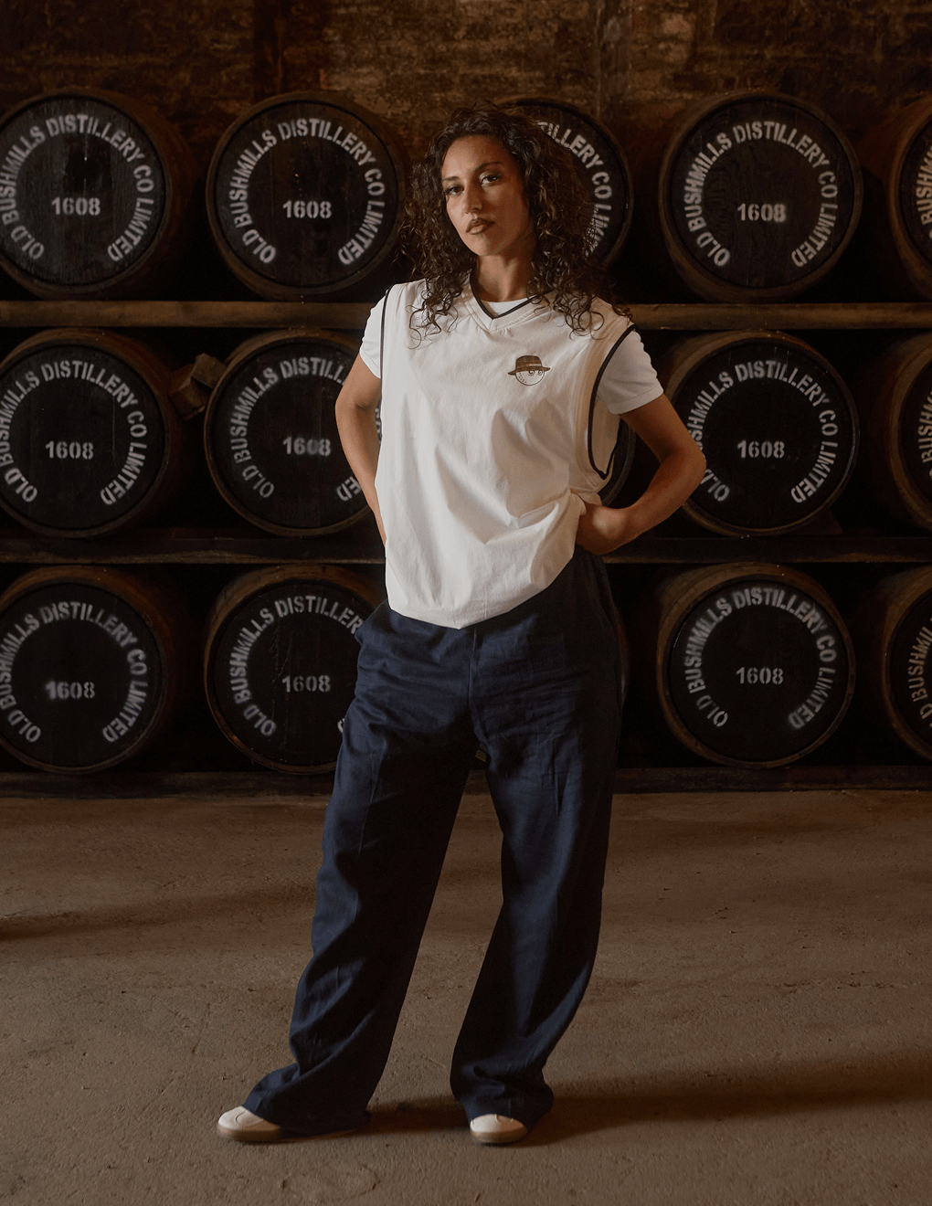 Woman posing in Bushmills x Malbon white vest in Bushmills distillery.