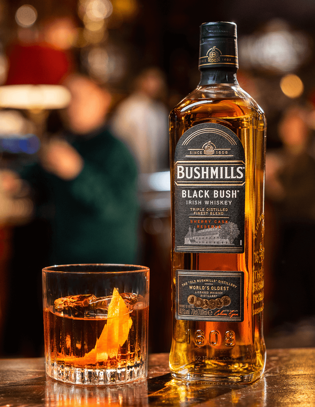 Bushmills Black Bush bottle with an Old Fashioned cocktail.