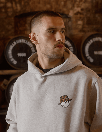 Male modeling Bushmills x Malbon hoodie with close up of front detail with Buckets cartoon.