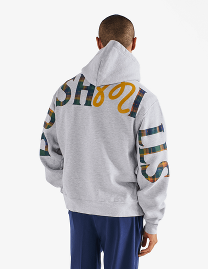 Model wearing of Bushmills x Malbon gray hoodie, showing back of hoodie with large Bushmills x Malbon collab logo.
