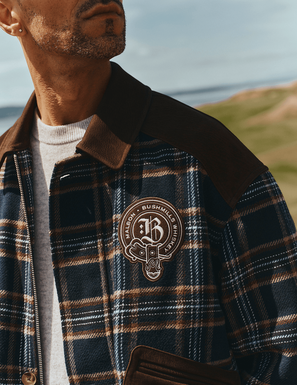 Close up view of Bushmills X Malbon Wool & Leather Jacket on a model on the golf course.
