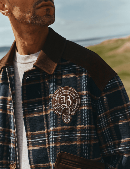 Close up view of Bushmills X Malbon Wool & Leather Jacket on a model on the golf course.